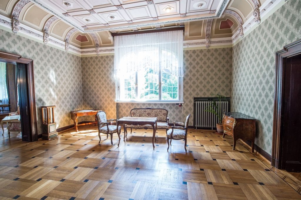 Salon z kasetonowym stropem i zabytkowymi meblami w porannym świetle